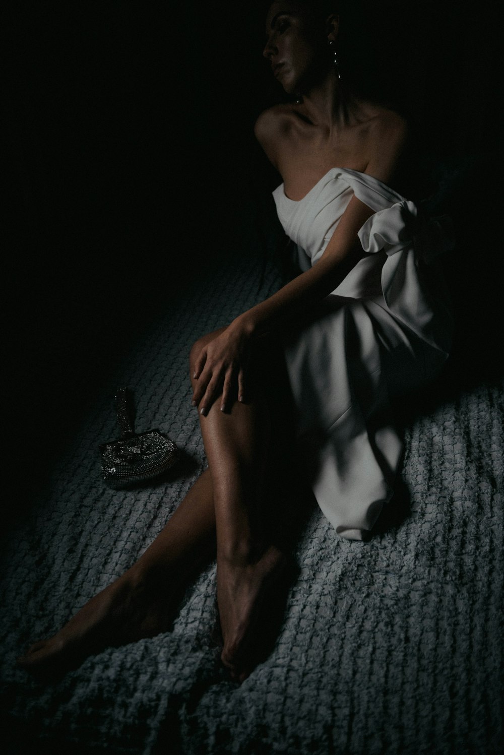 a woman in a white dress sitting on a bed