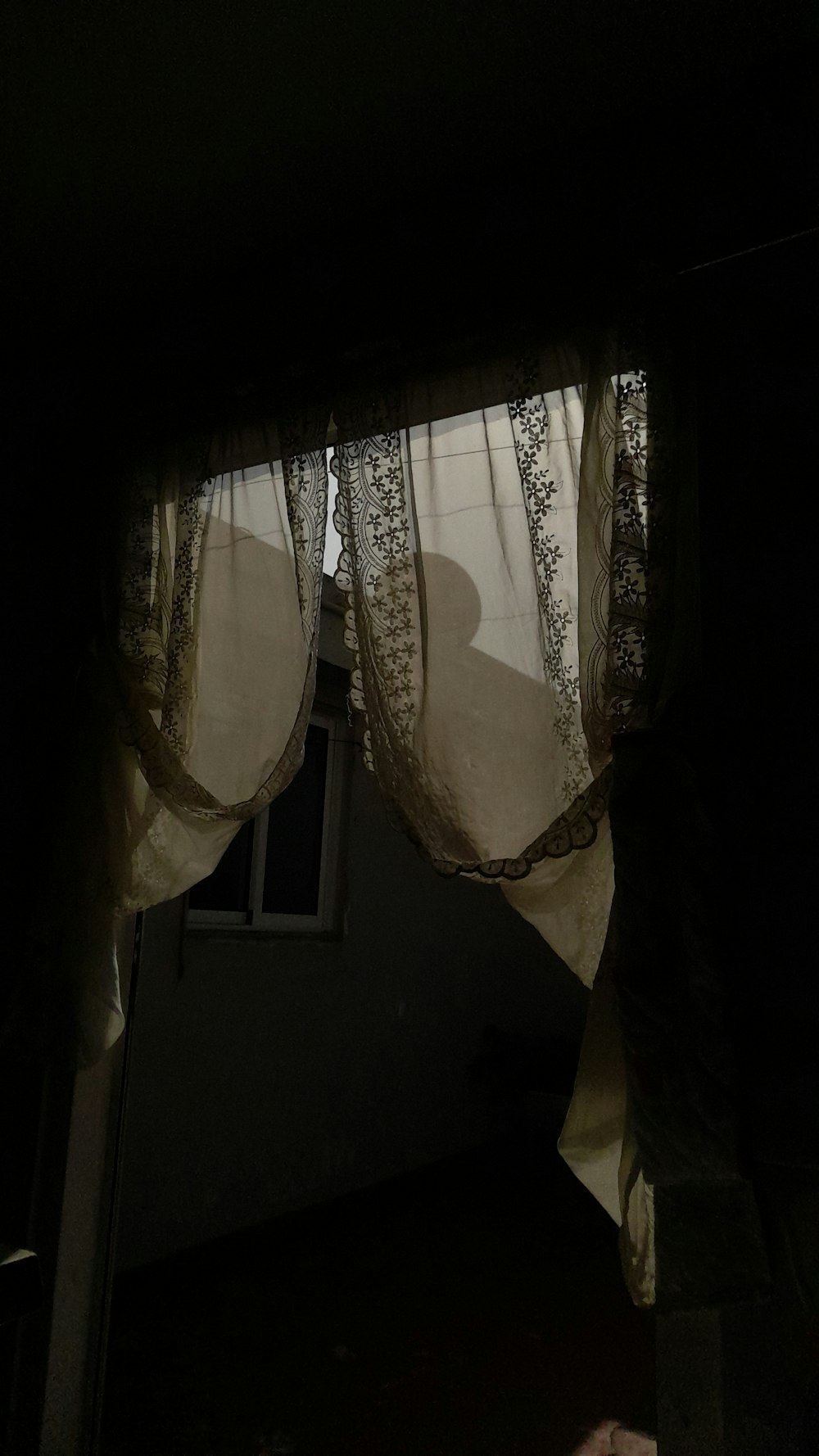 a dark room with a window and curtains