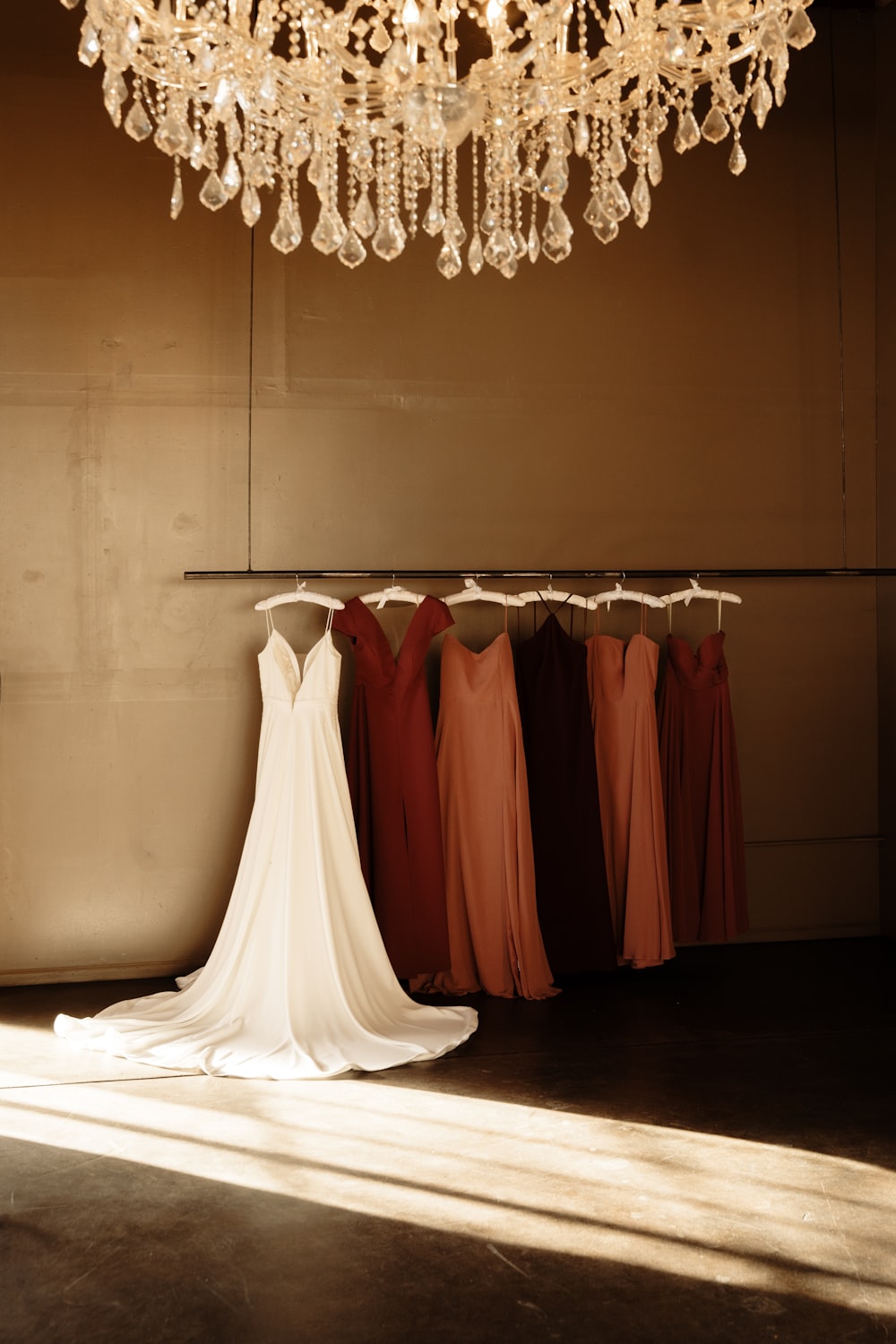 a bride's dress hangs in front of a chandelier