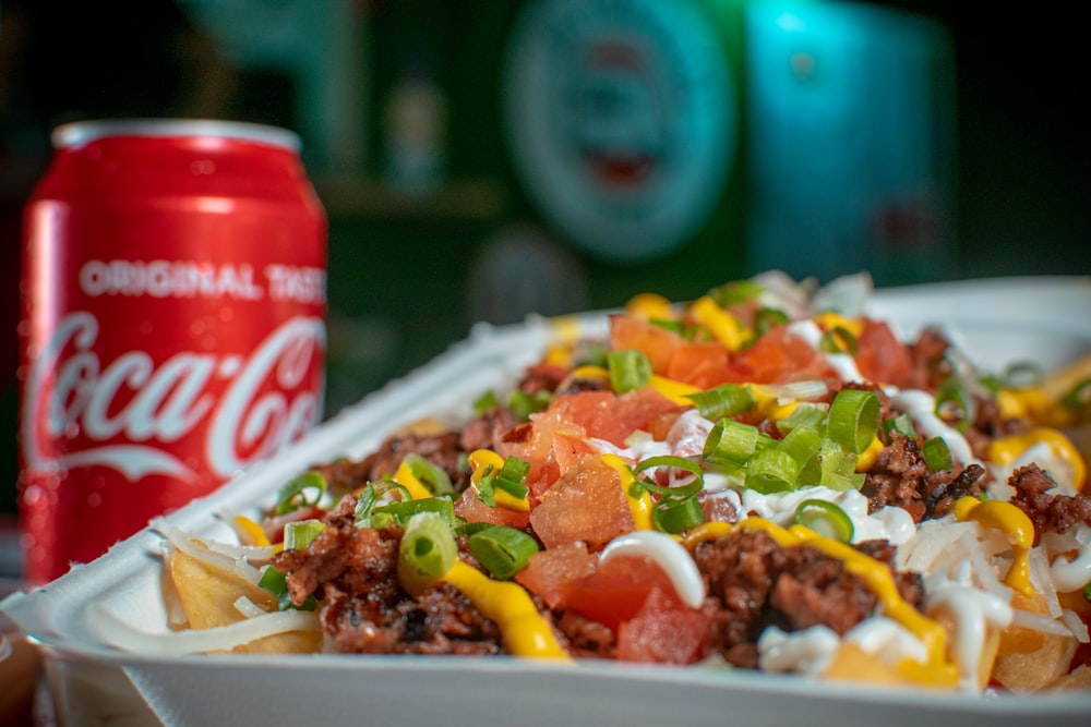 a close up of a tray of food with a can of soda