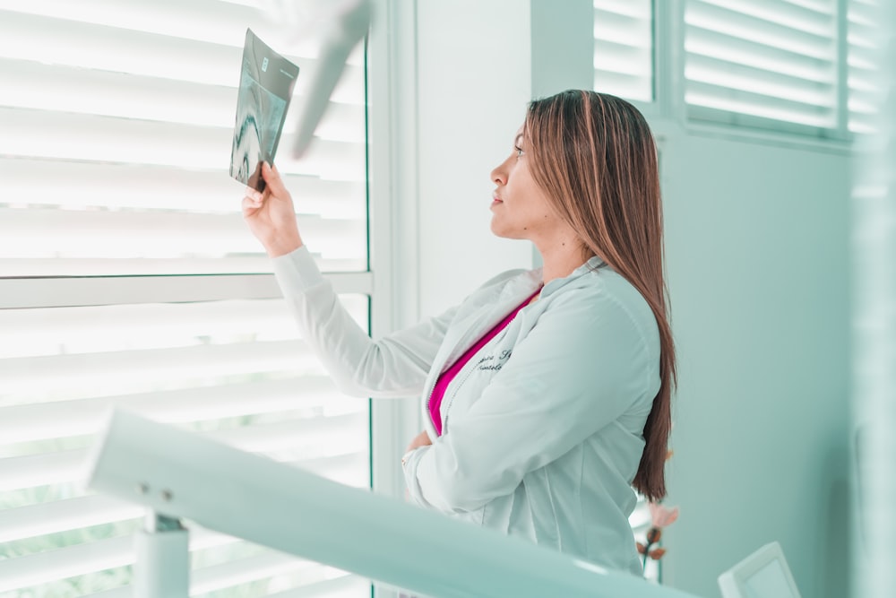 a woman in a white lab coat looking out a window