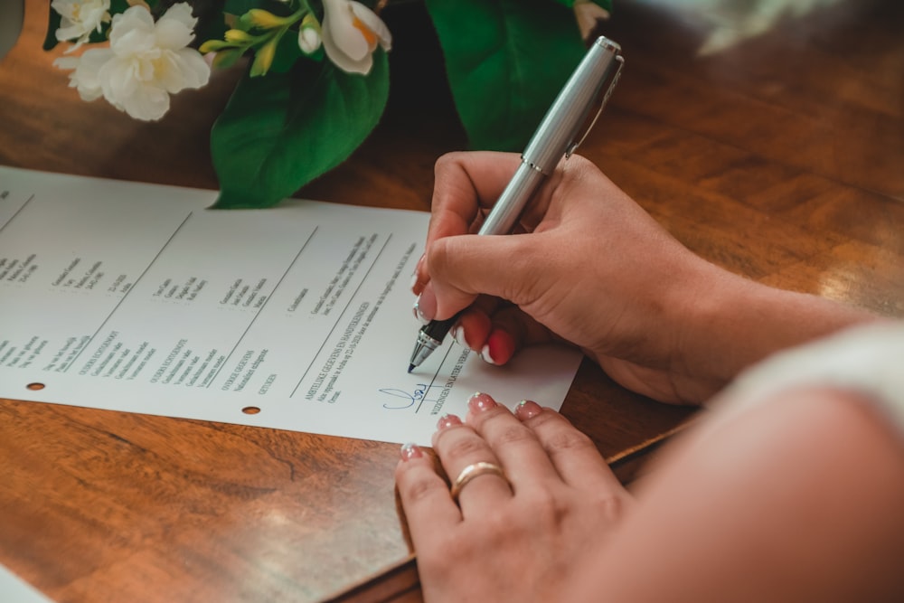 a person writing on a piece of paper with a pen