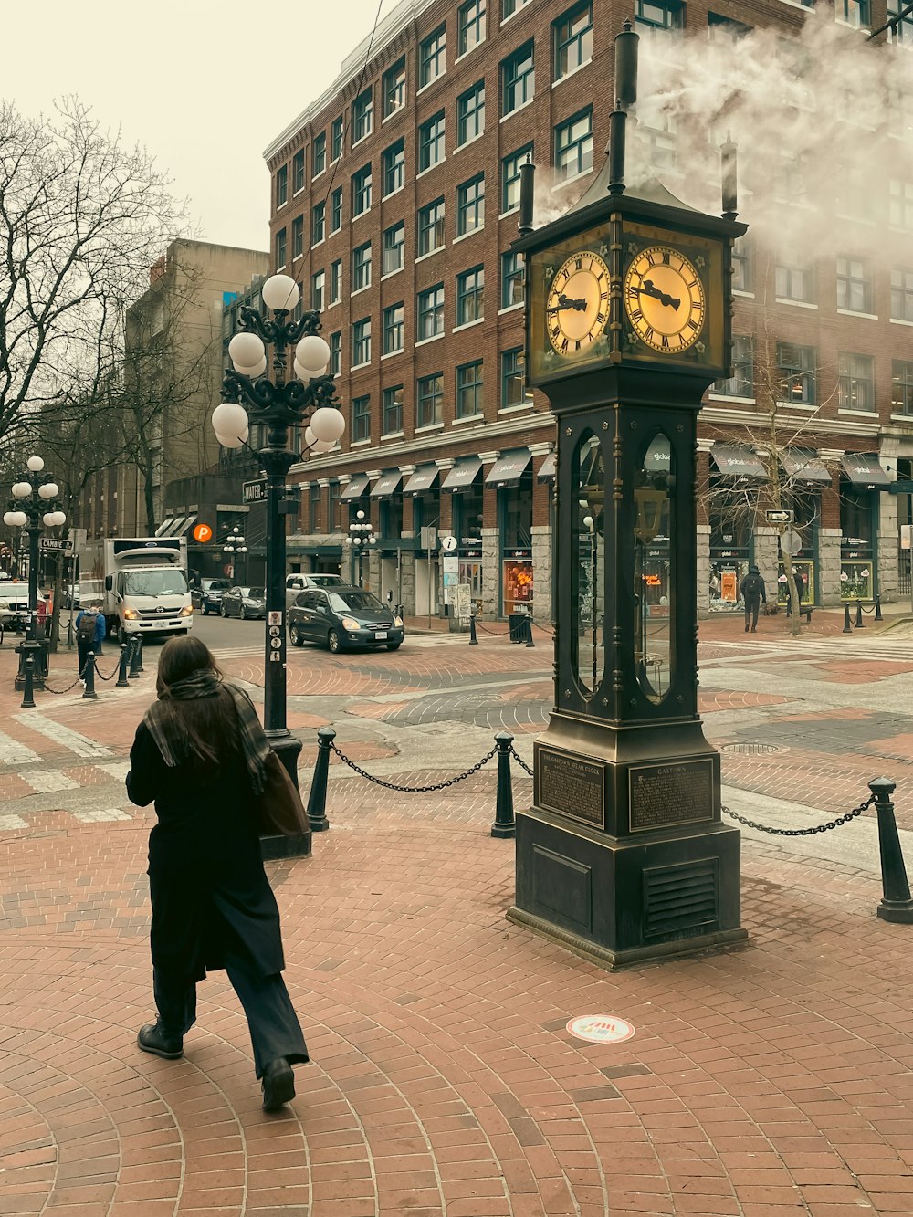 a woman walking down a street past a clock tower