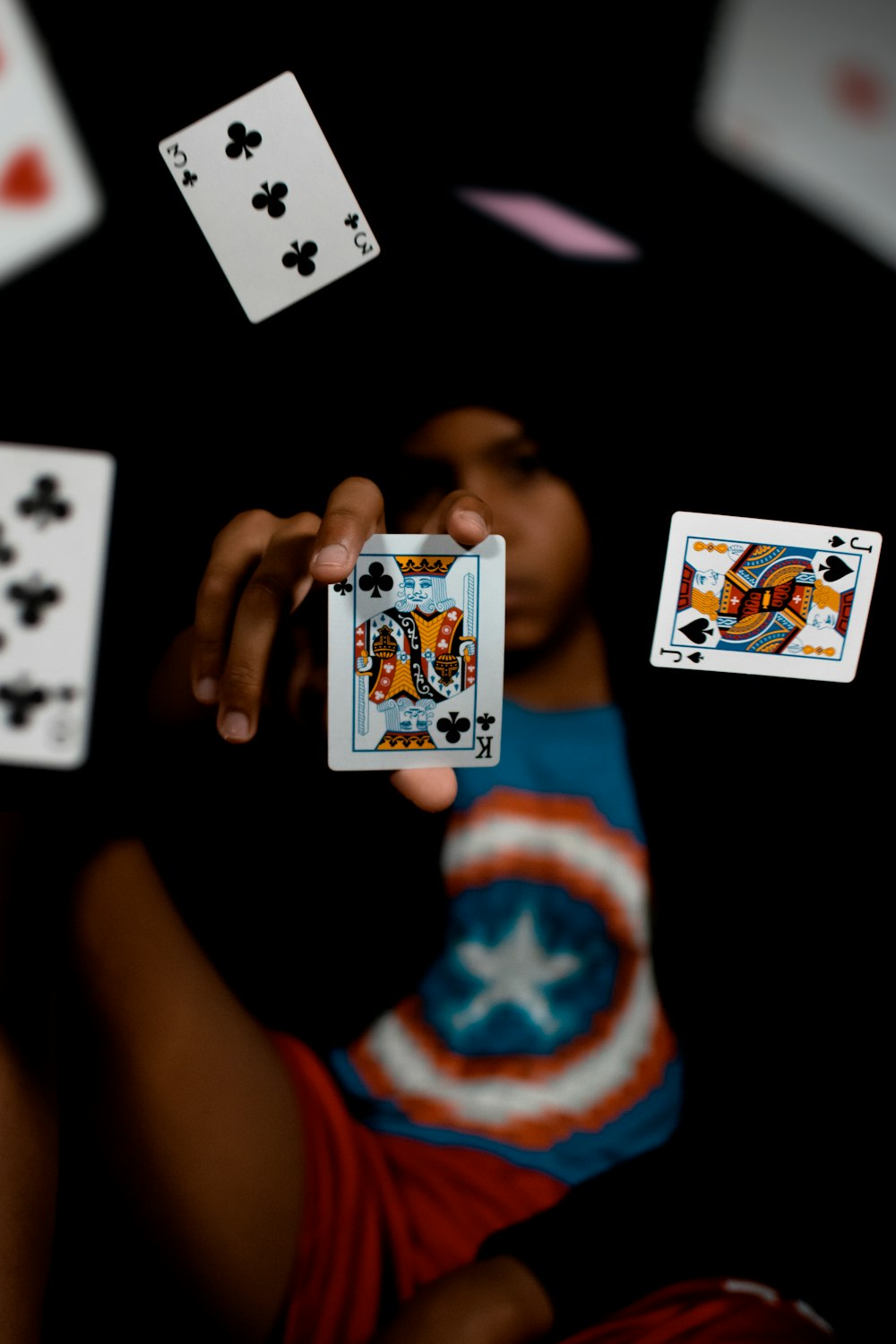 a person holding a card in their hand surrounded by playing cards