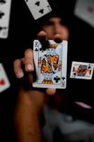 a person holding a playing card surrounded by playing cards