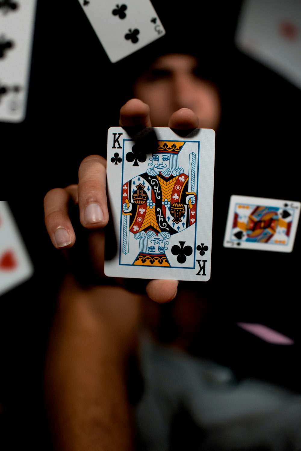 a person holding a playing card surrounded by playing cards