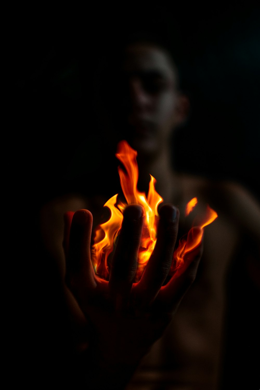 a man holding out his hand with fire in it