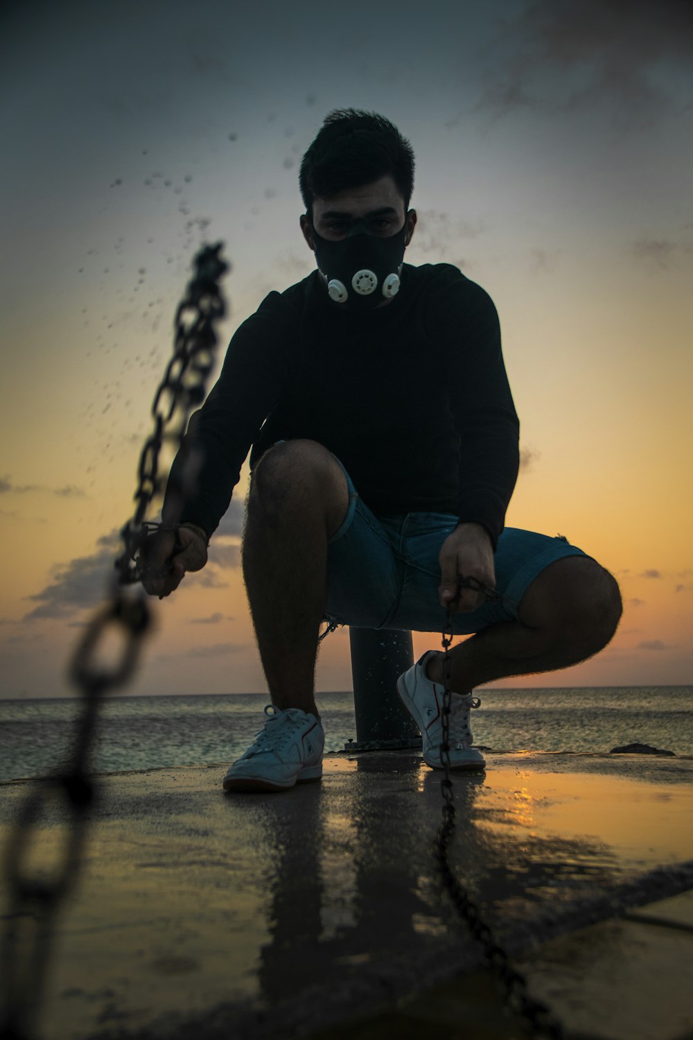 a man wearing a gas mask sitting on a dock