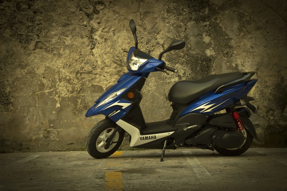 a blue scooter parked in front of a stone wall