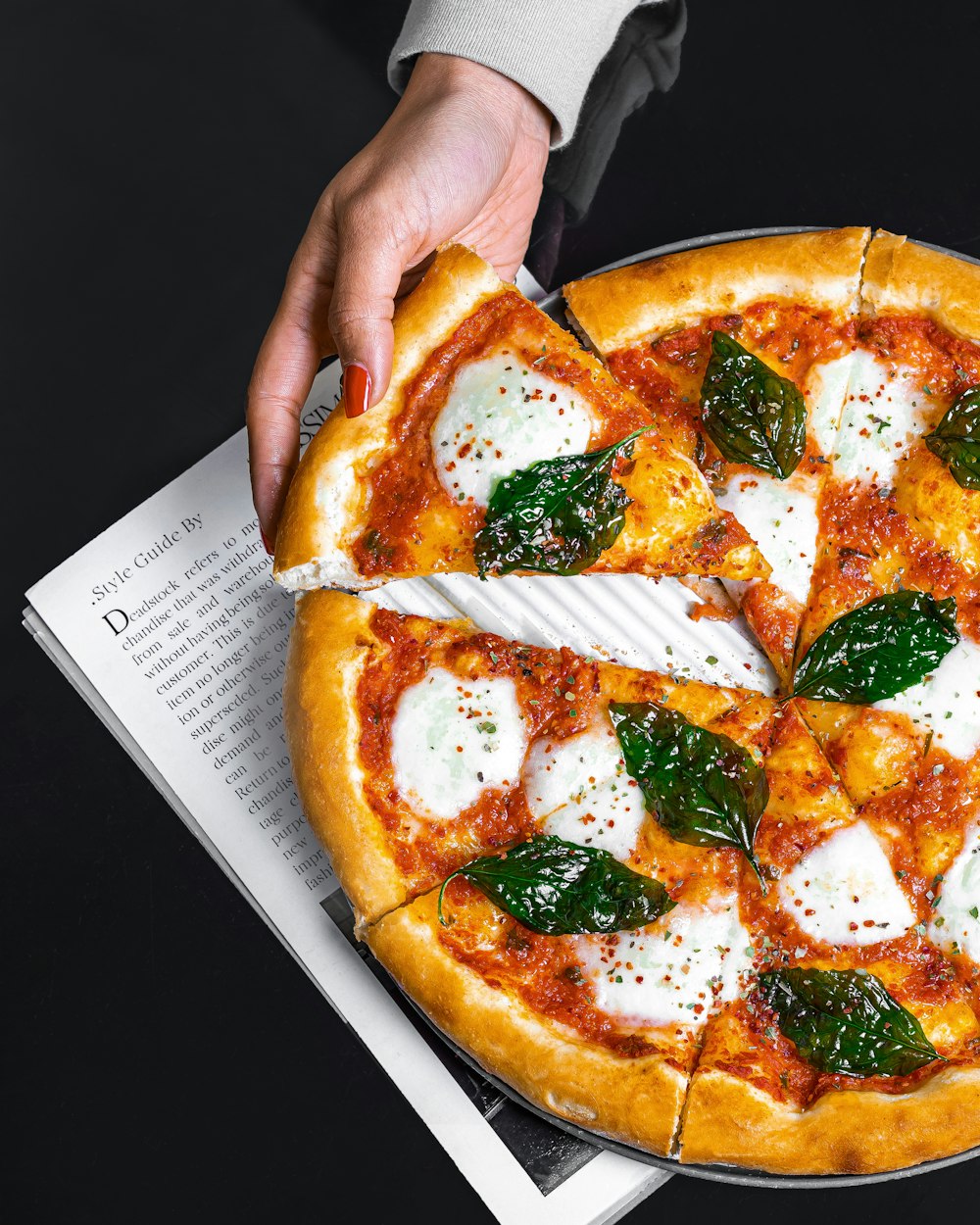 a person holding a pizza with cheese and spinach on it