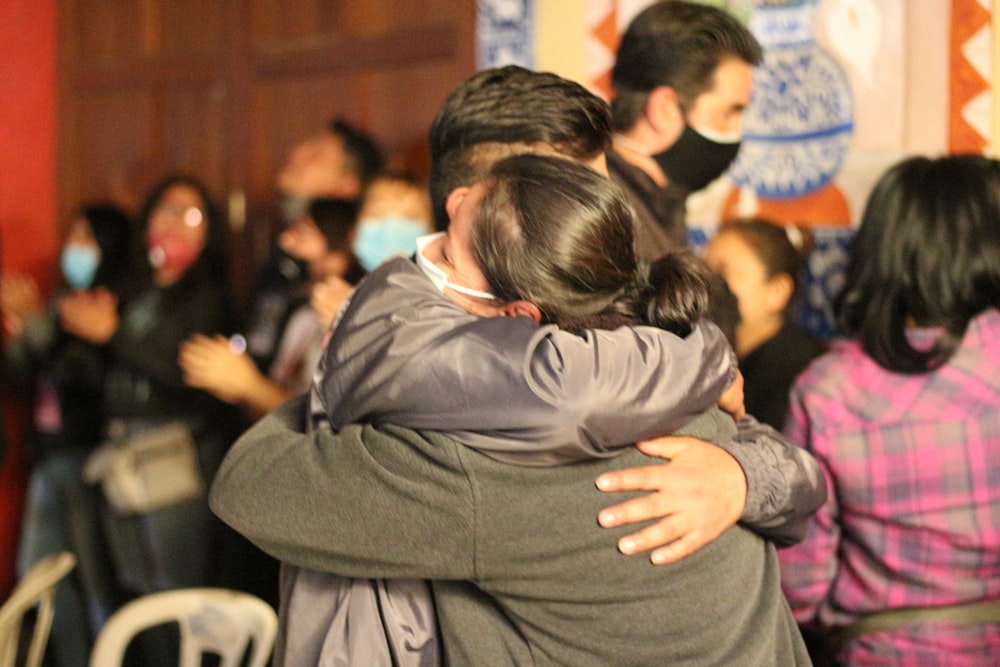 two people hugging each other in front of a crowd of people