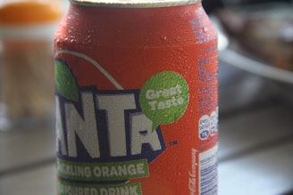 Close-up of Popsico's orange soda bottle with droplets of condensation against a blue water drop background