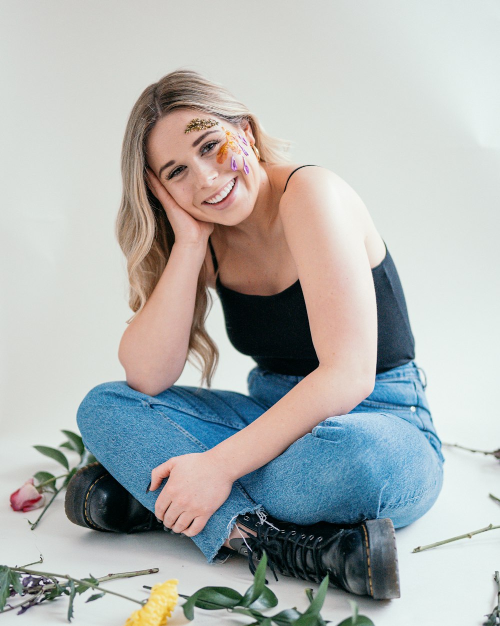 a woman sitting on the ground with flowers around her