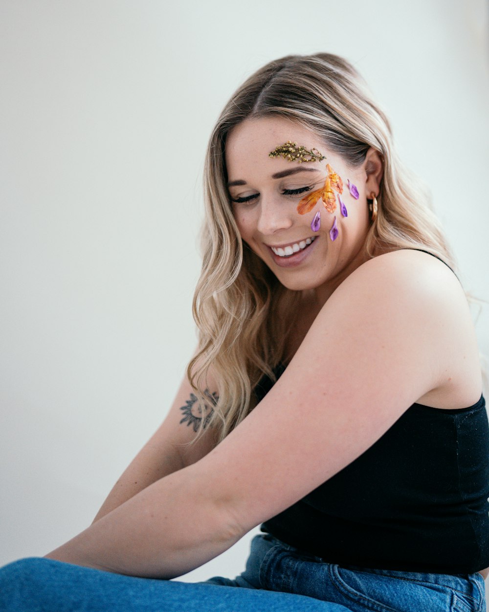 a woman sitting on the floor with her face painted