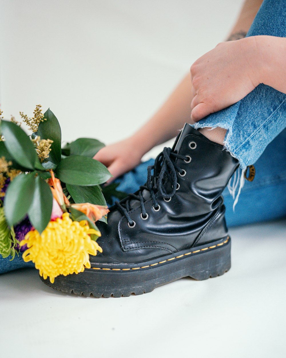 a pair of black boots with a bouquet of flowers