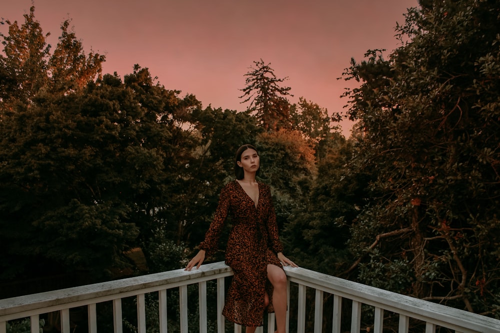 a woman standing on a balcony with trees in the background