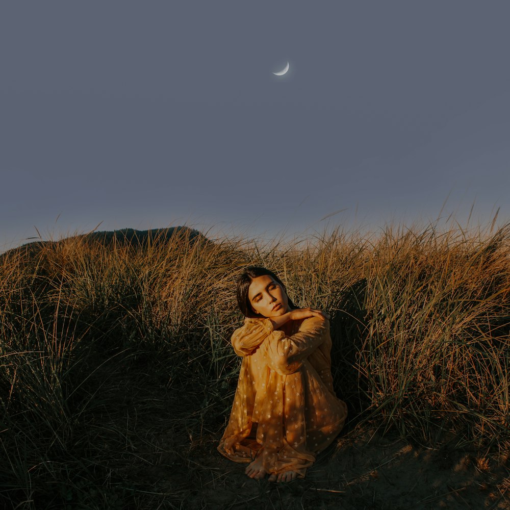 a woman in a yellow dress sitting in a field