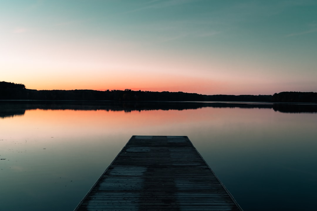 a dock sitting on top of a lake next to a forest, Sunrise over Lake Sagatagan with dock
