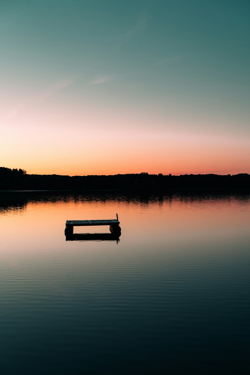 a boat floating on top of a lake at sunset