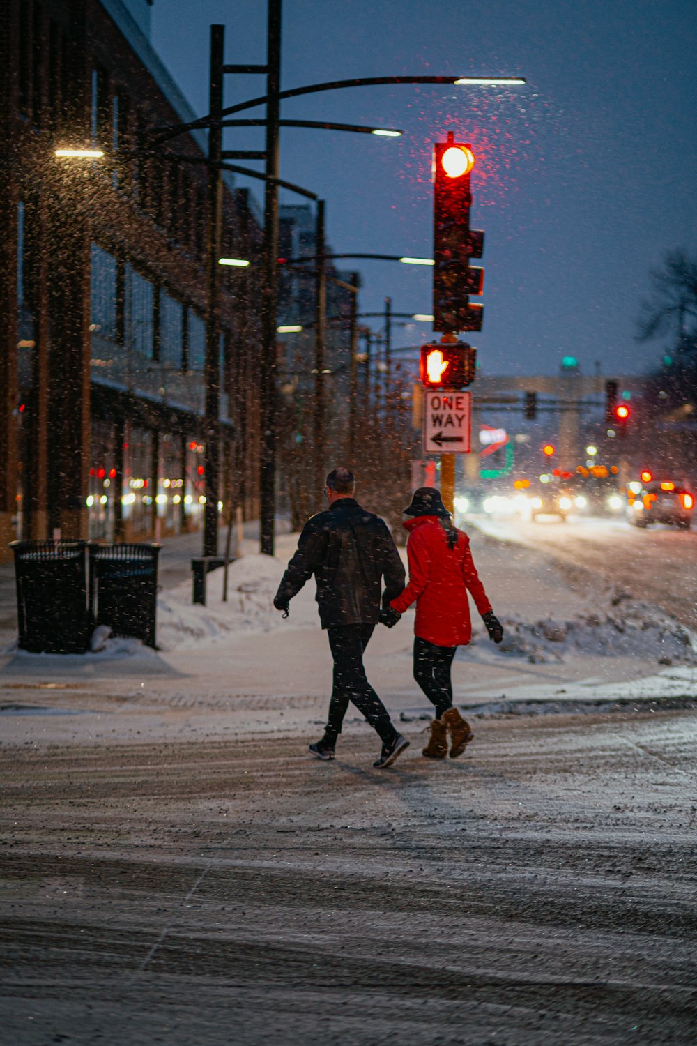 a couple of people walking across a snow covered street