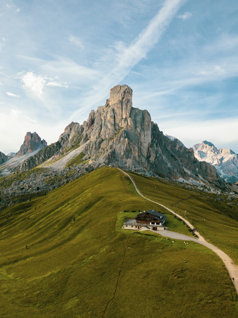 Una casa su una collina erbosa con le montagne sullo sfondo