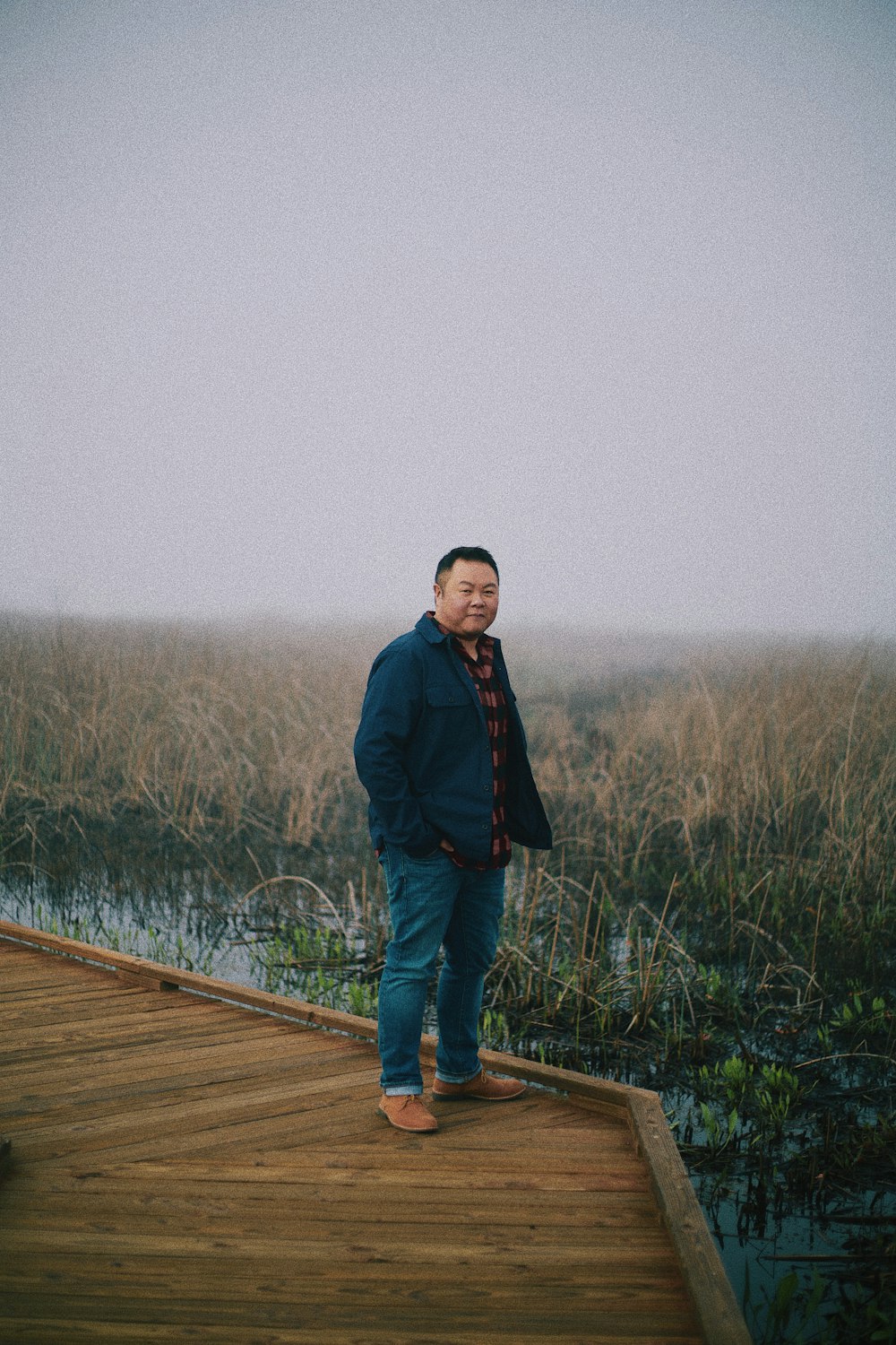 a man standing on a dock in front of a marsh