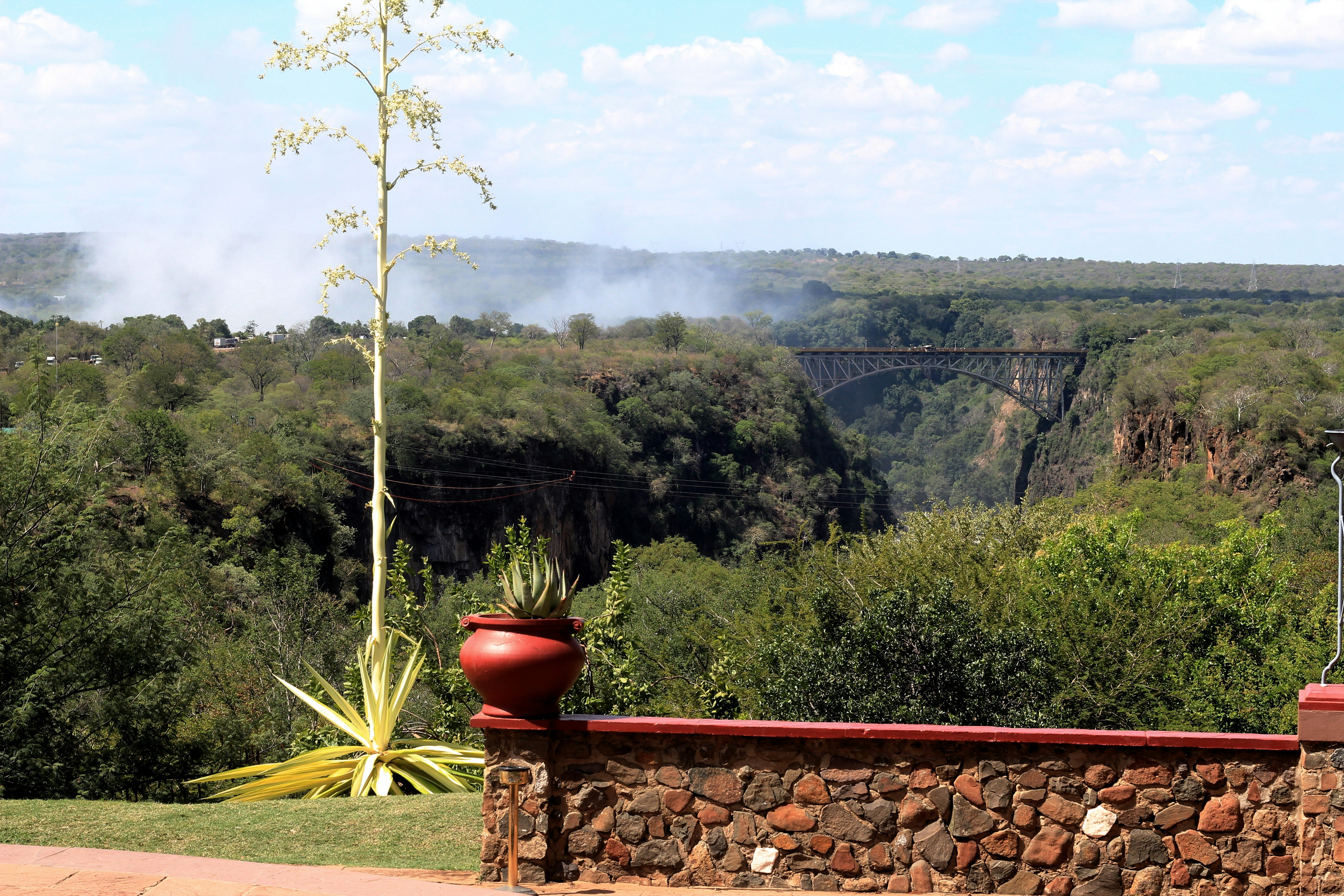 a red vase sitting on top of a stone wall