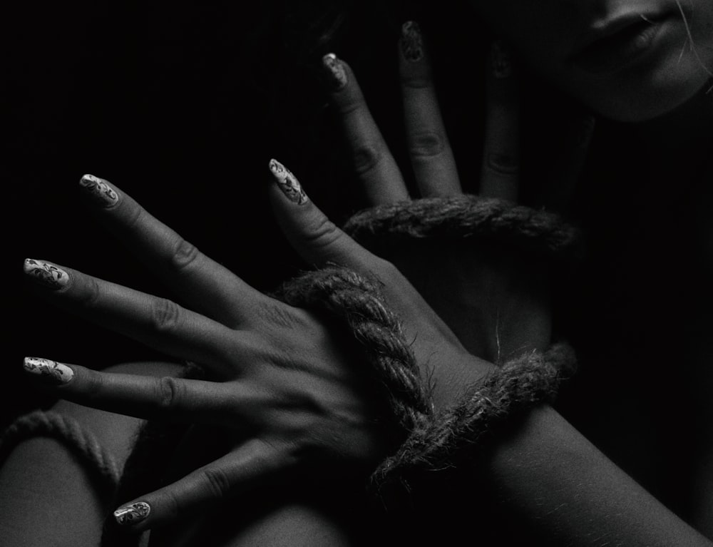 a black and white photo of two hands wrapped in rope