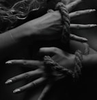 two hands tied up with rope and nails