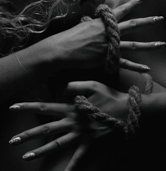 two hands tied up with rope and nails