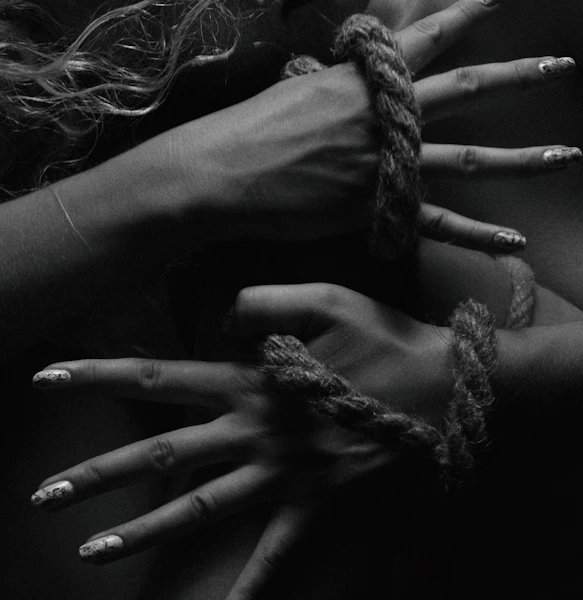two hands tied up with rope and nails