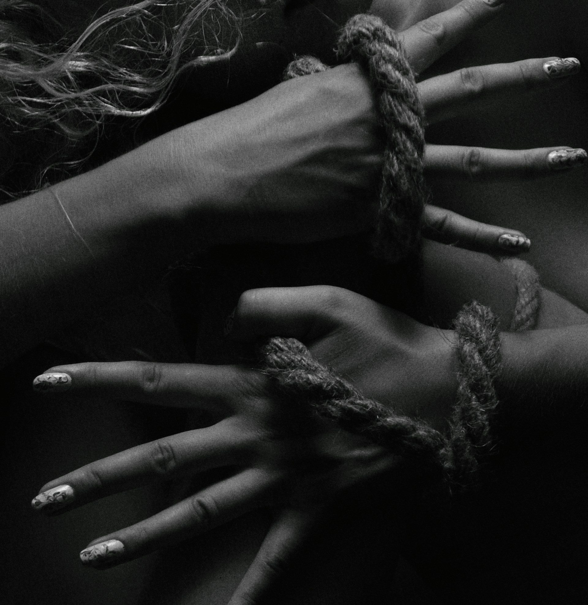 two hands tied up with rope and nails
