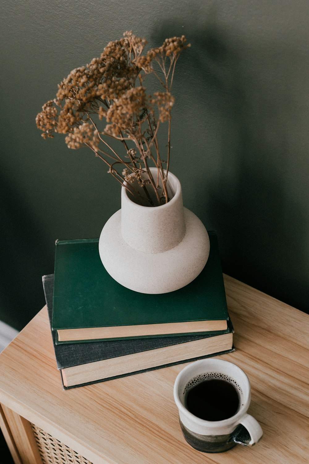 커피 한 잔 옆 테이블 위에 놓인 책 더미