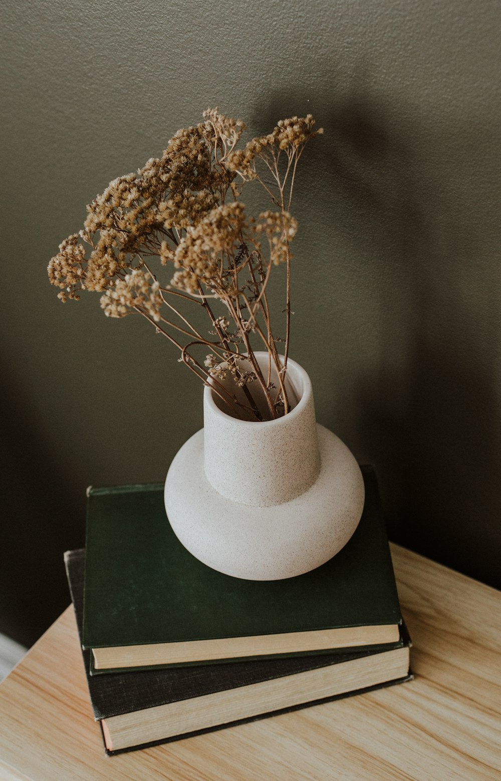 a white vase sitting on top of a stack of books