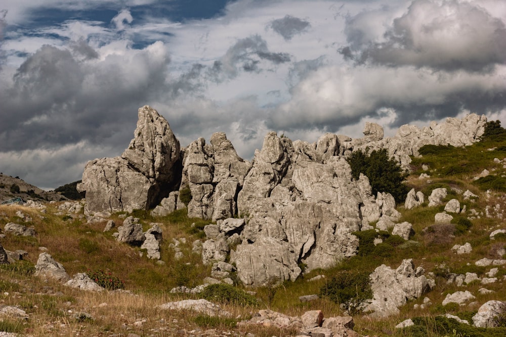 a group of rocks sitting on top of a grass covered hillside