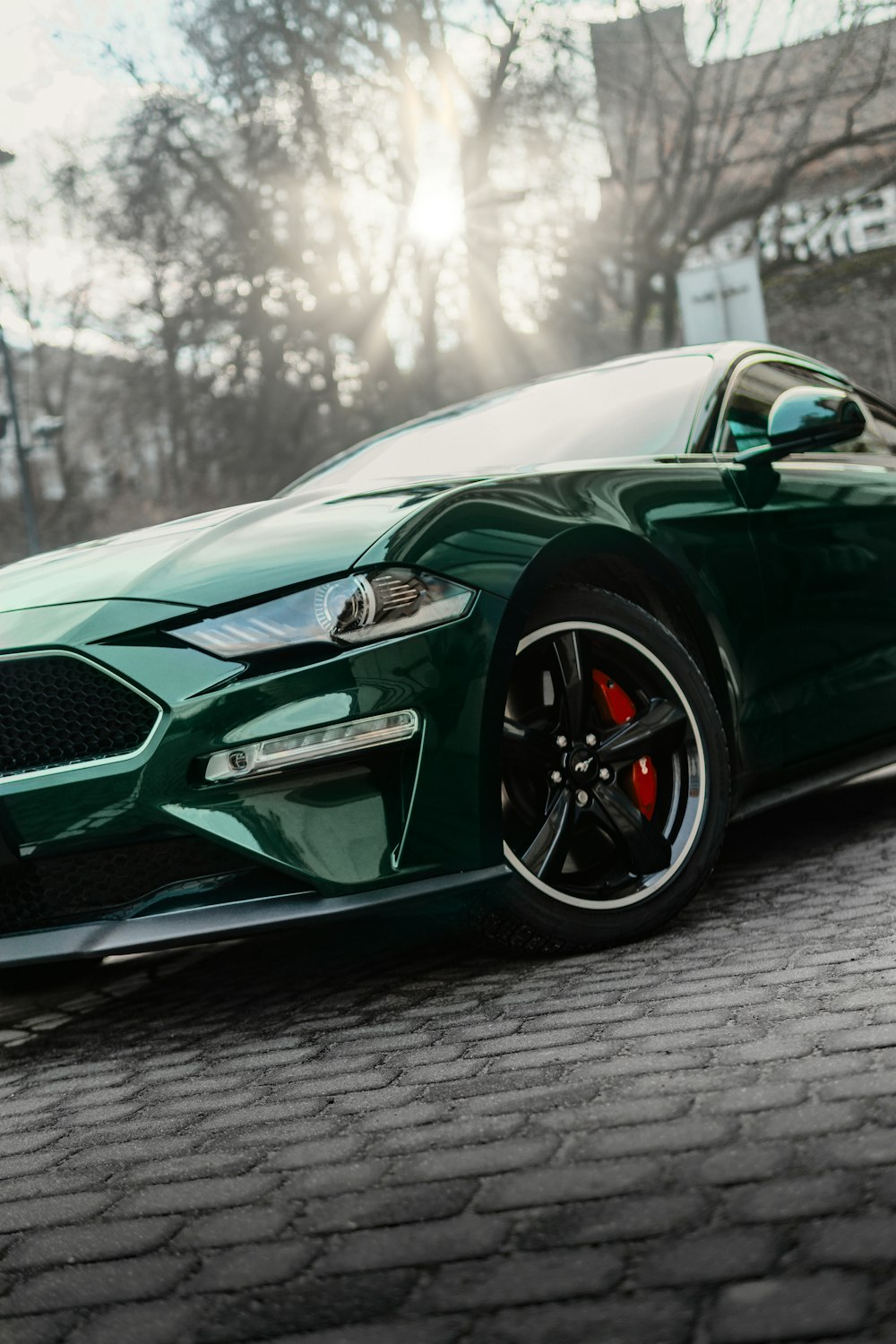 a green sports car parked on a brick road