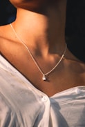 A model wearing a delicate necklace and matching earrings in warm sunlight.