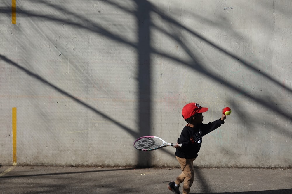 a young boy holding a tennis racquet on top of a tennis court