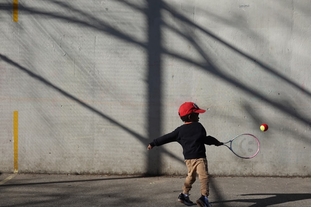 a young boy hitting a tennis ball with a racquet