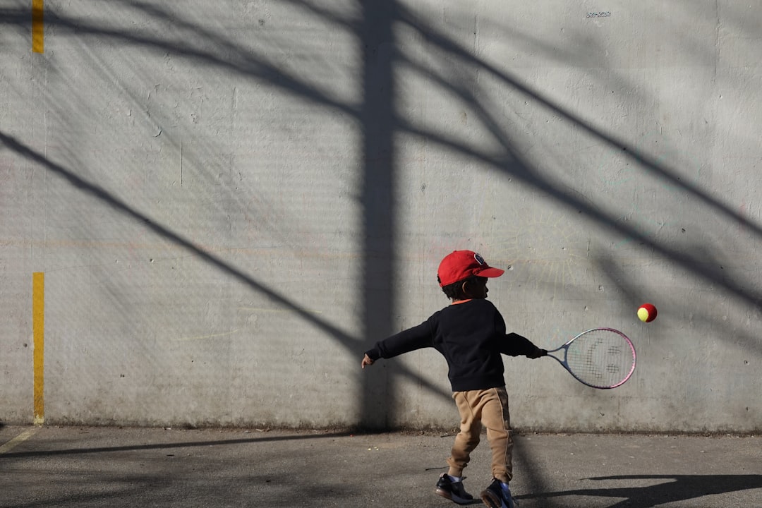 A little boy playing tennis by himself