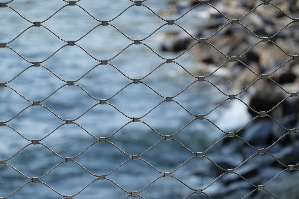 a chain link fence next to a body of water