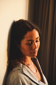 A serene woman practicing mindfulness in a softly lit room with warm cream and coral tones.