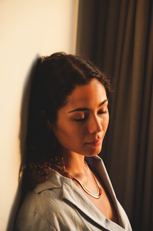 A serene woman meditating in a softly lit room with pastel pink and beige tones