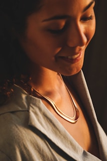 A woman smiling softly, wearing subtle earrings from Joyas Freda, bathed in warm natural light.
