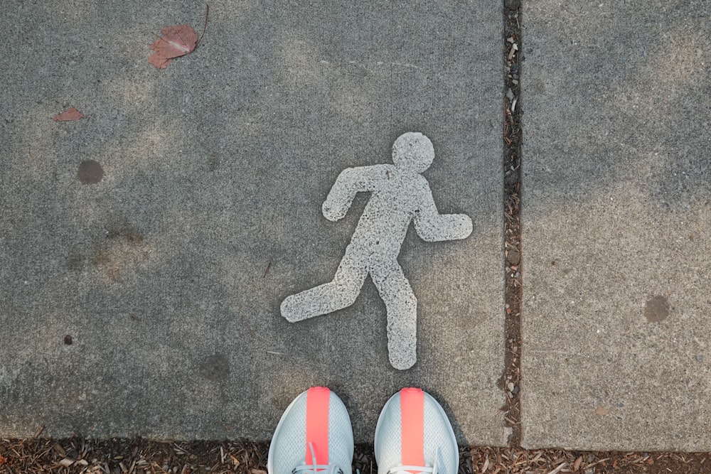 a pair of shoes standing in front of a walk sign