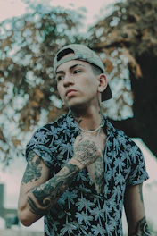 a man with tattoos standing in front of a tree