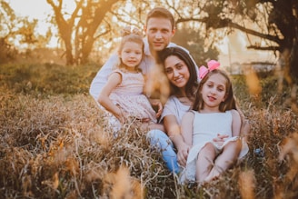 a man and two little girls sitting in a field