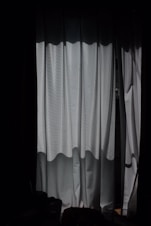 a dark room with a window and a curtain
