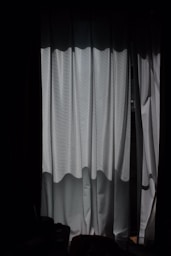 a dark room with a window and a curtain