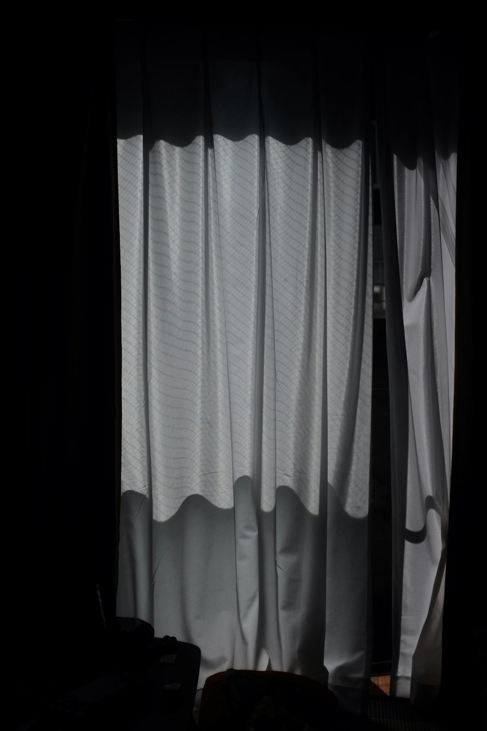 a dark room with a window and a curtain